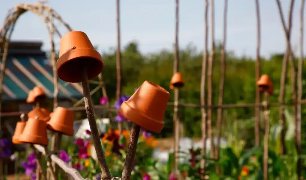 Pourquoi les jardiniers expérimentés plantent un pot retourné sur un piquet : ce vieux signal oublié peut vous éviter une erreur coûteuse